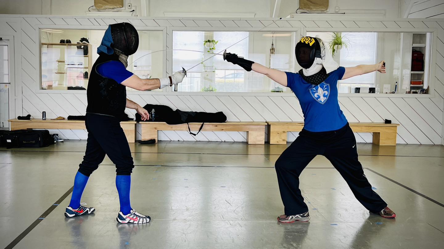 A woman classical HEMA fencer getting a private fencing lesson with the Italian foil